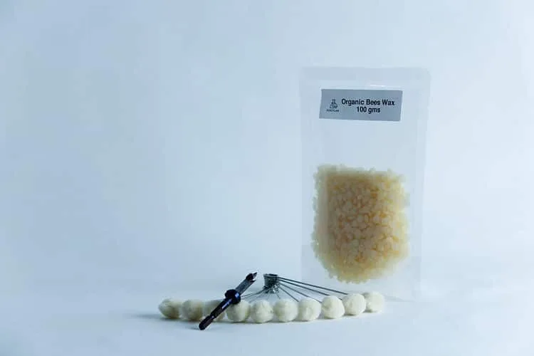 A Log dowel inoculation kit mushrooms is displayed against a light background, featuring a pouch labeled Organic Bees Wax 100 gms next to white beads on metal pins—essential components for the kit.