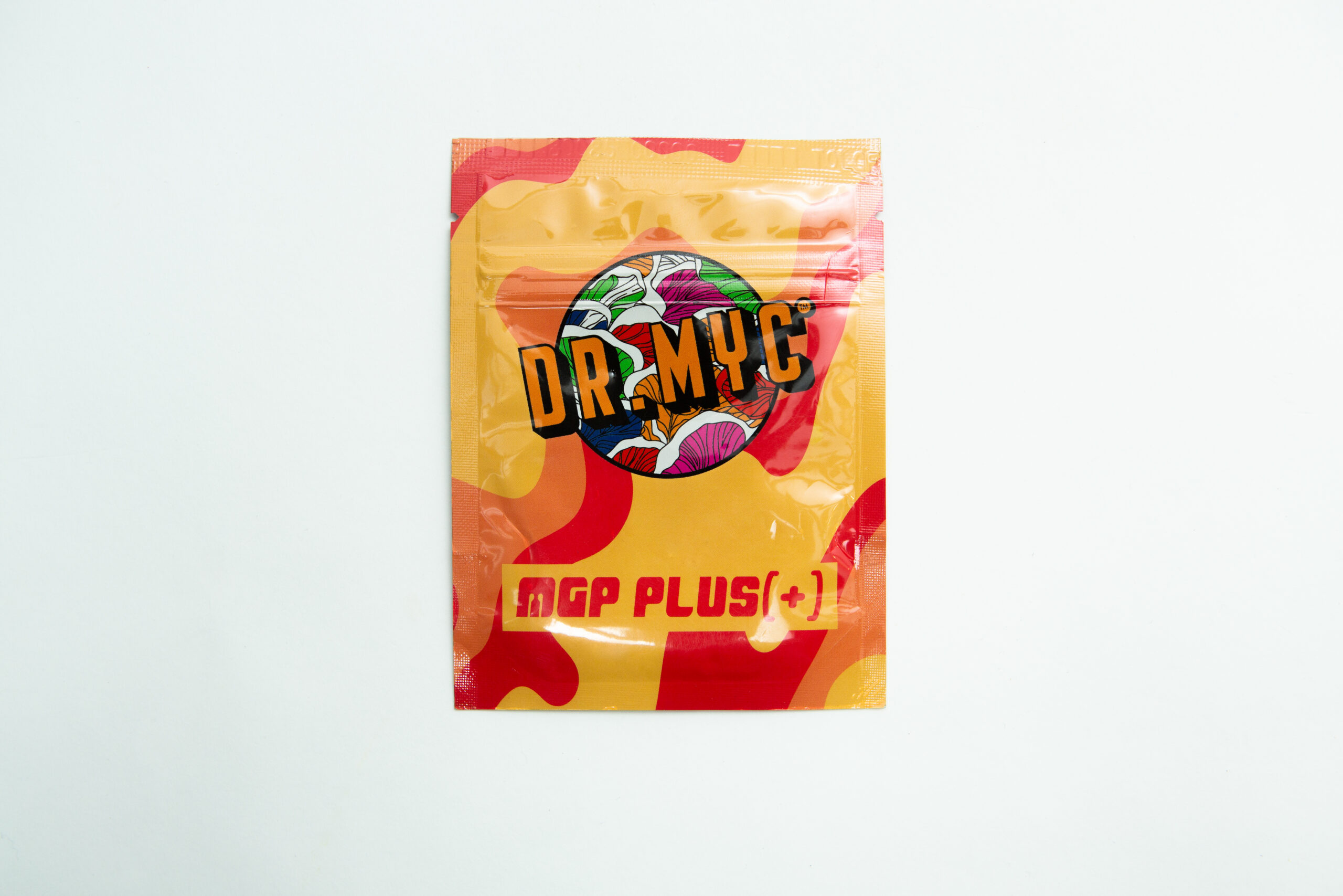 A vibrant DRMyc Adaptive Liquid Culture Premix packet features a bold logo over abstract red and yellow, ideal for mushroom growers seeking a convenient liquid culture solution from drmyc.