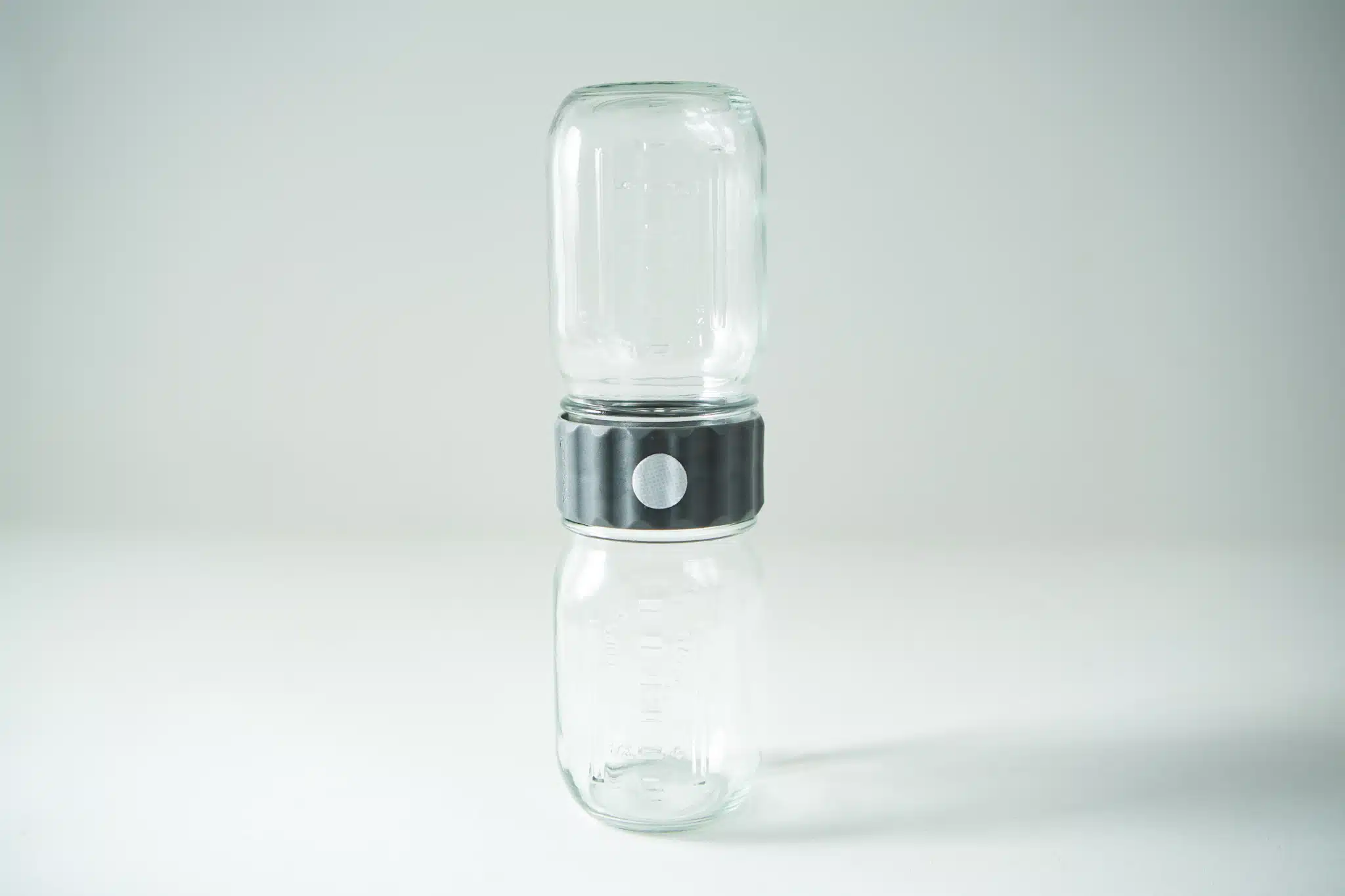 Two empty glass jars are stacked vertically with the Plant Cell Biocouplerâ„¢ Neck connector joining them, set against a plain background.