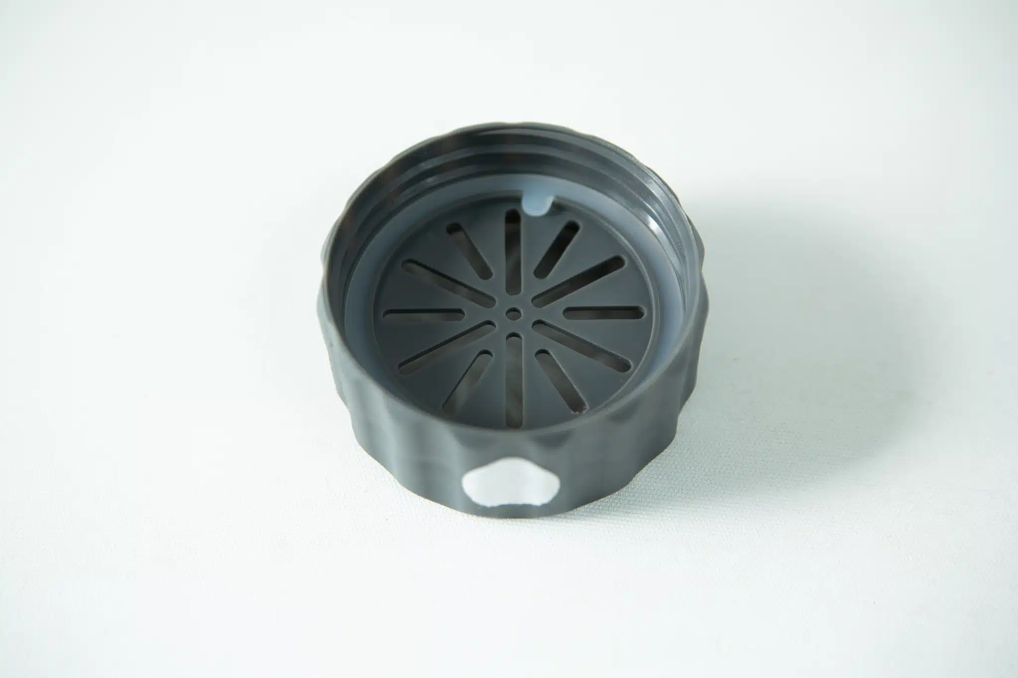 A black, slotted, circular plastic cap—ideal as a Neck accessory for the Plant Cell Biocoupler™ system—is shown on a plain white background.