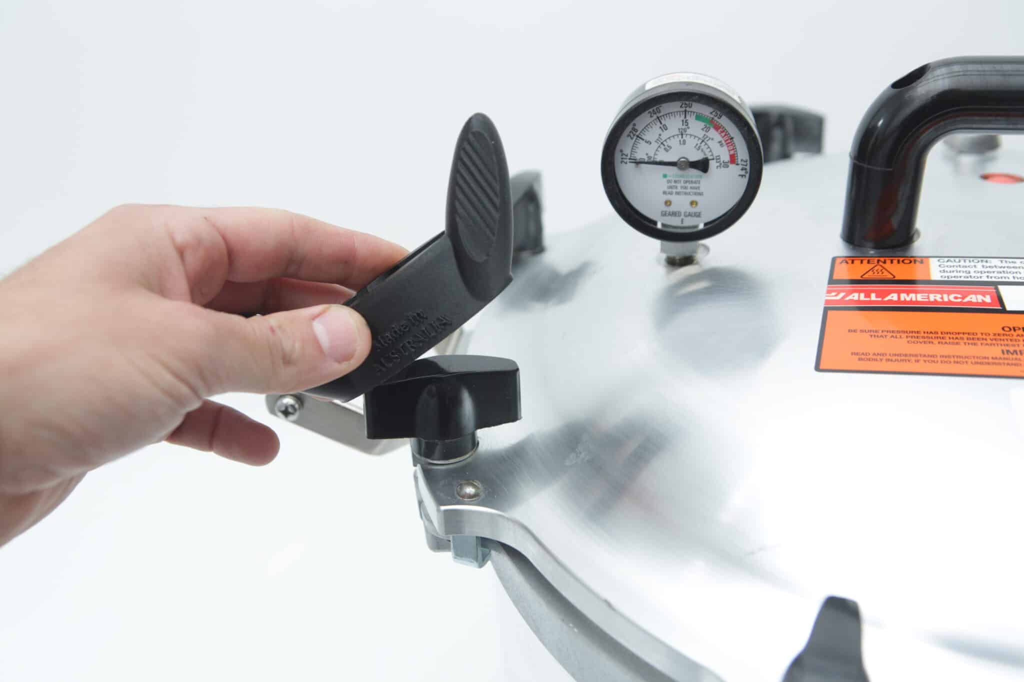 Using the Rootlab Original 3D Printed Wingnut Wrench for All American Steriliser, a hand secures the metal lid with a visible pressure gauge on top.