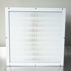 The Laminar Flow Hood HEPA Airfilter H14 w/prefilter 60x60x35cm, featuring a white frame and mesh screen, sits on a metal surface against a neutral wall—ideal for use in laminar flow hoods.
