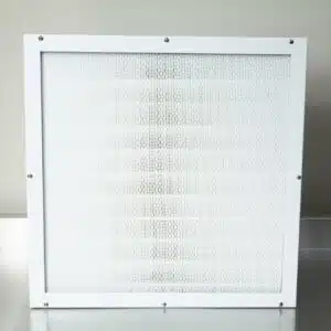 The Laminar Flow Hood HEPA Airfilter H14 w/prefilter 60x60x35cm, featuring a white frame and mesh screen, sits on a metal surface against a neutral wall—ideal for use in laminar flow hoods.
