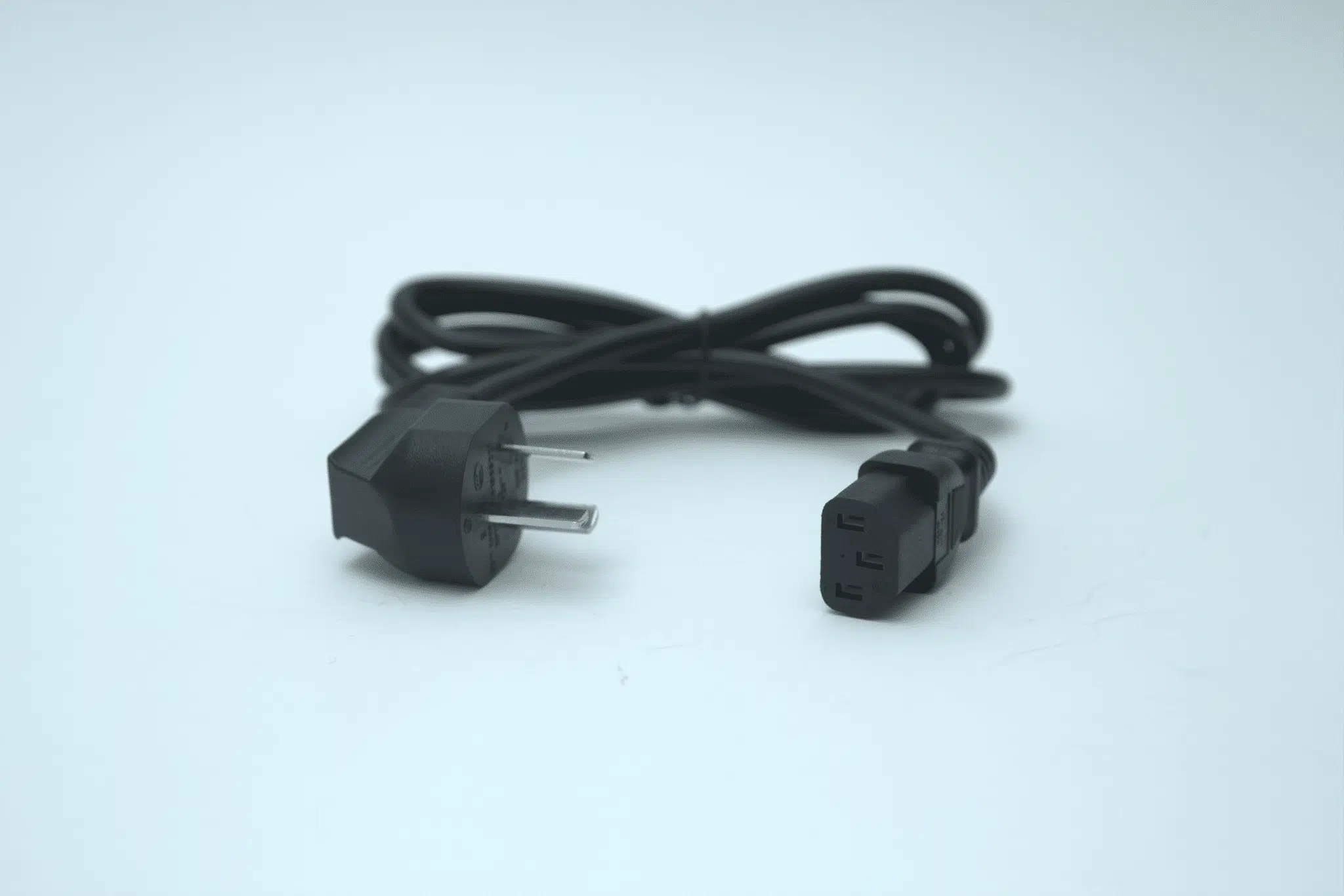 A black power cord with two-prong plug and IEC connector, coiled on a light background—ideal for powering lab equipment such as the Laminar Flow Hood HEPA Airfilter H14 w/prefilter 60x60x35cm.