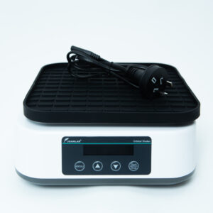 A digital laboratory orbital shaker with a black power cord placed on top, against a white background.