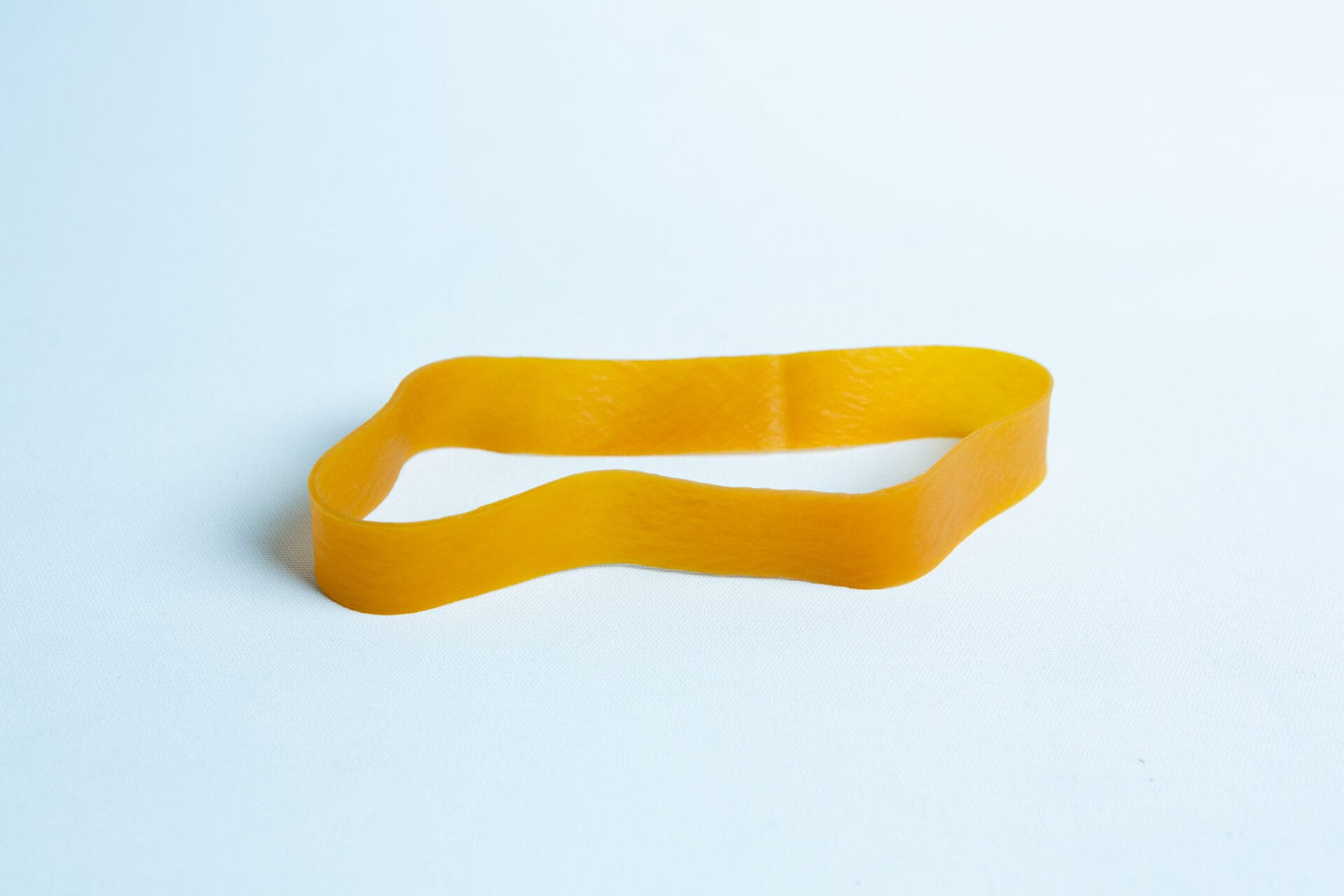 Ten Fruiting Rubber Bands for Mushroom Growing are reusable and perfect for mushroom setups. The bands are yellow and shown lying flat on a light blue surface.