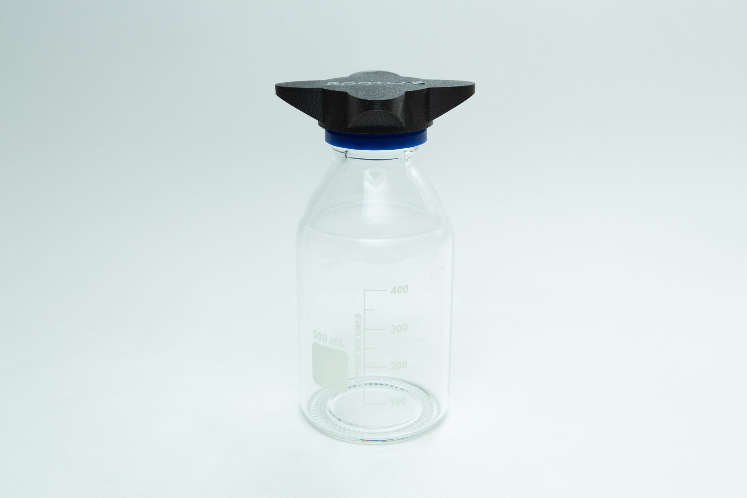 A clear glass laboratory bottle with measurement markings and a blue-capped black lid on a white background.