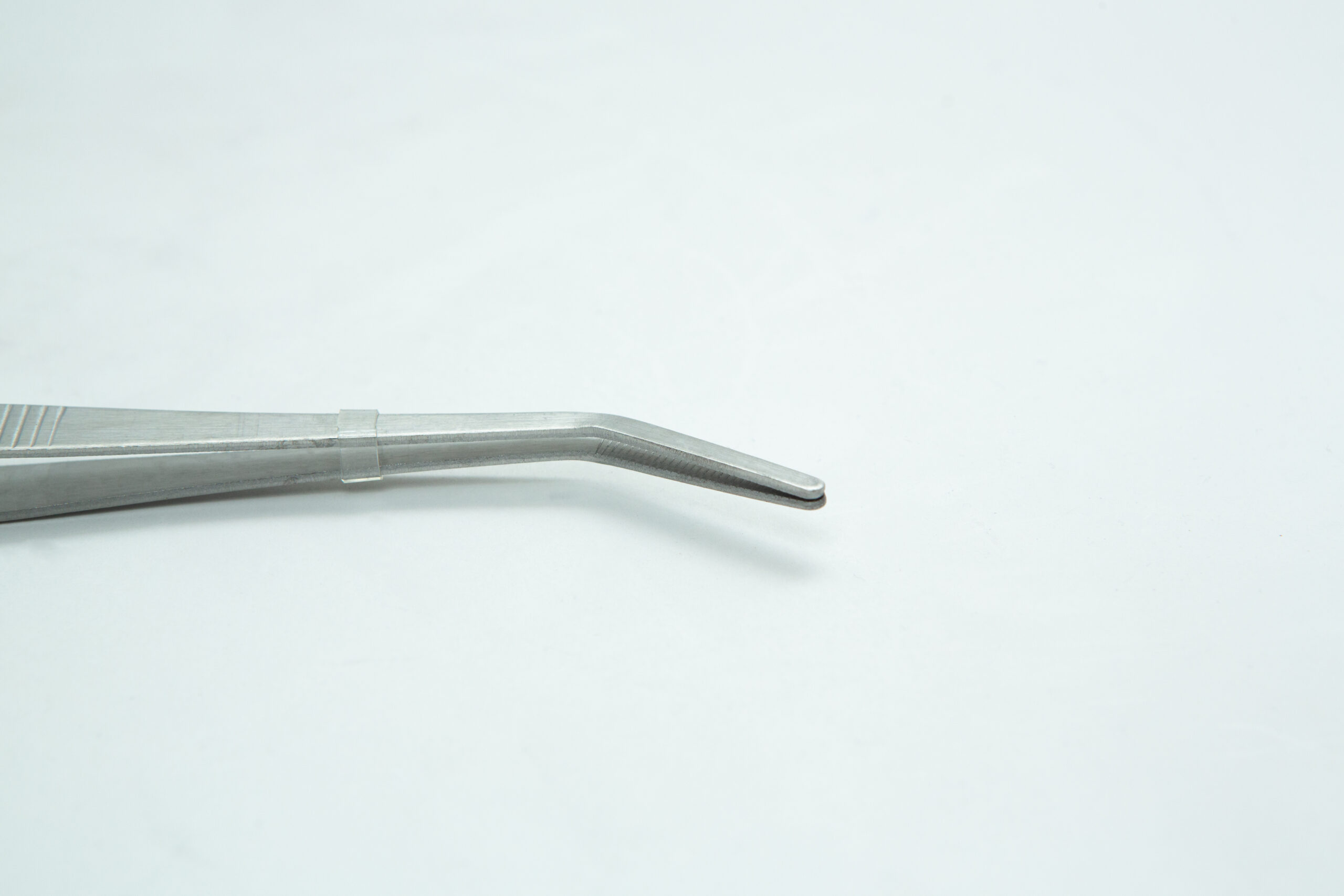 A close-up of a metal tweezer with a bent tip on a plain white background.