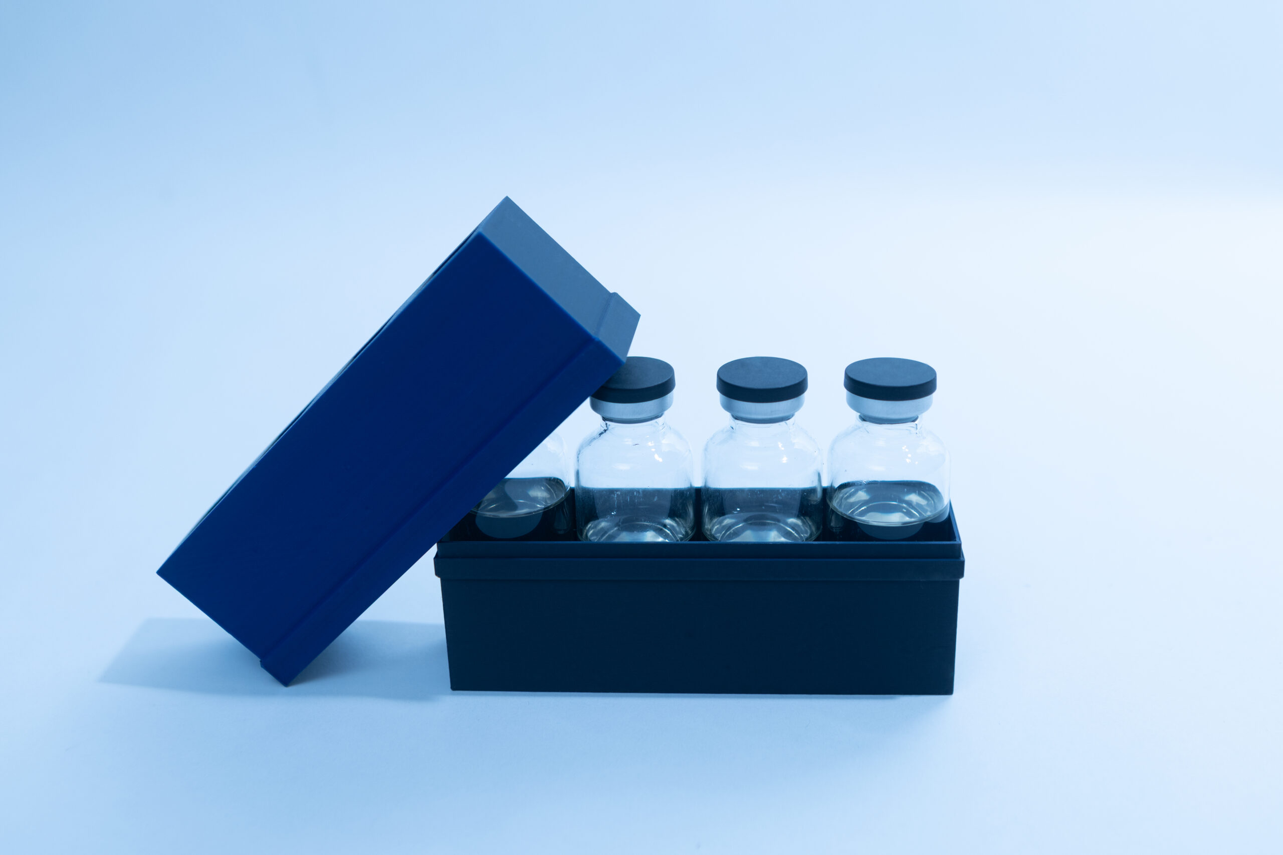 Four glass vials with black caps in a black box, one side of the box lid is open.