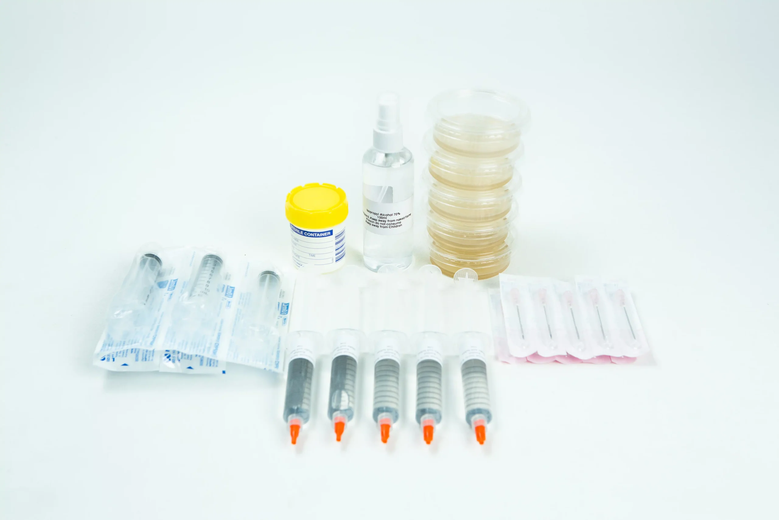 The Spore Print to Spore Syringe Transfer Kit, featuring syringes, a spore syringe, petri dishes, a spray bottle, and a yellow-lidded container, is displayed on a white surface.