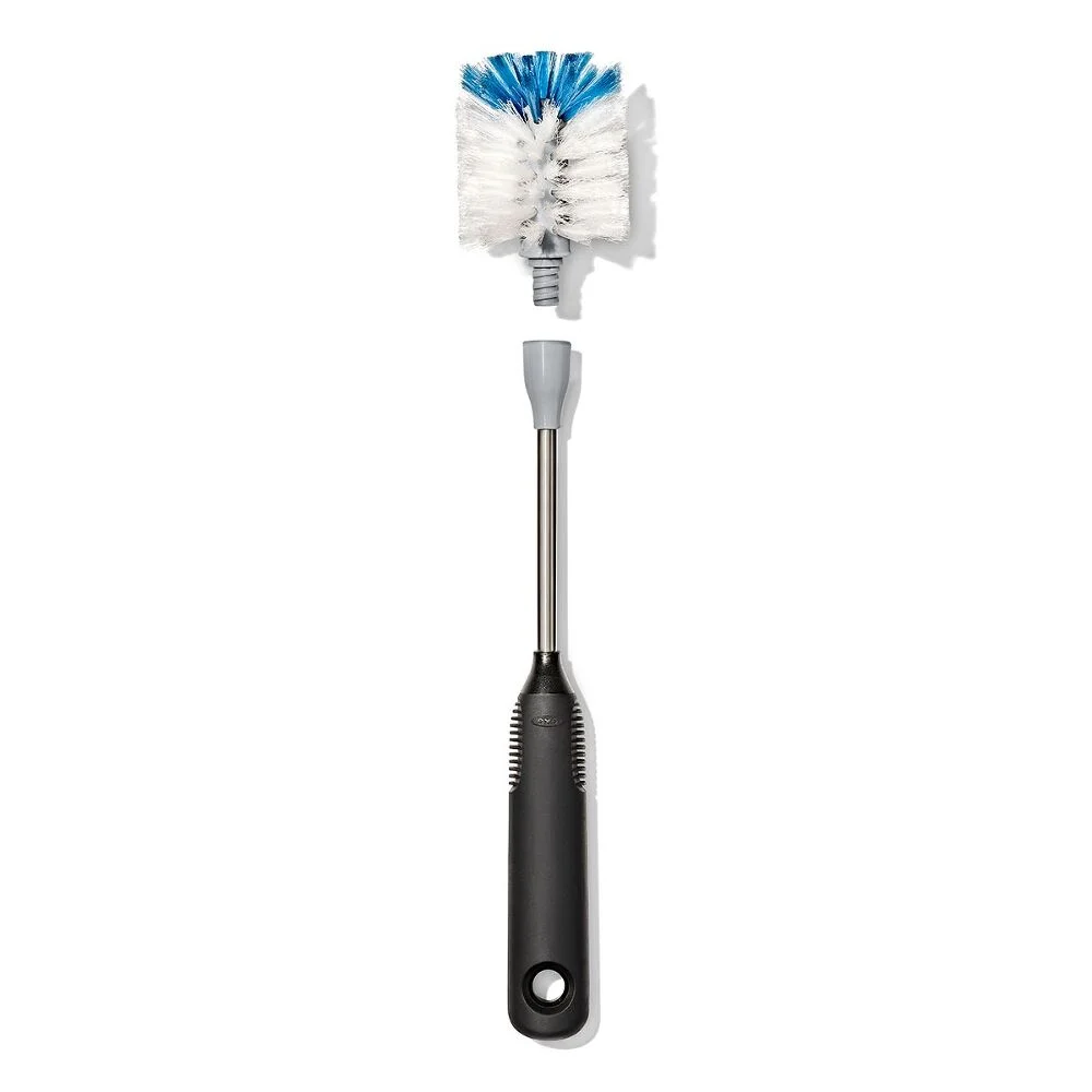 A dish brush with a black handle, silver neck, and white bristles tipped with blue.